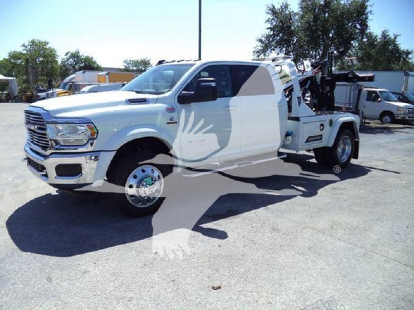 Ram 2500 heavy-duty pickup truck with a winch setup, white color, side crane equipment visible in bed, front chrome grille, large side mirrors, wheel covers.