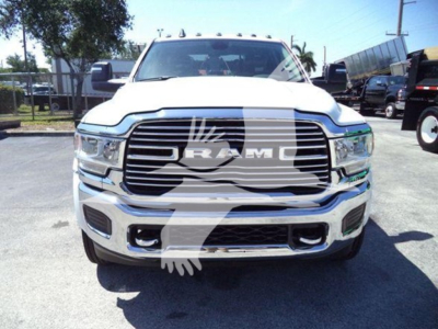 Front view of a white 2024 Ram truck showing large grille with RAM logo and chrome bumper, dealership lot background