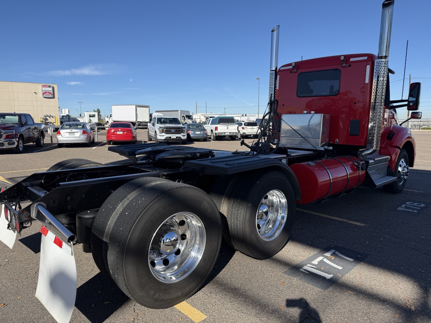Kenworth T880 conventional daycab tractor shown from rear-left side with red cab and dual rear axles.