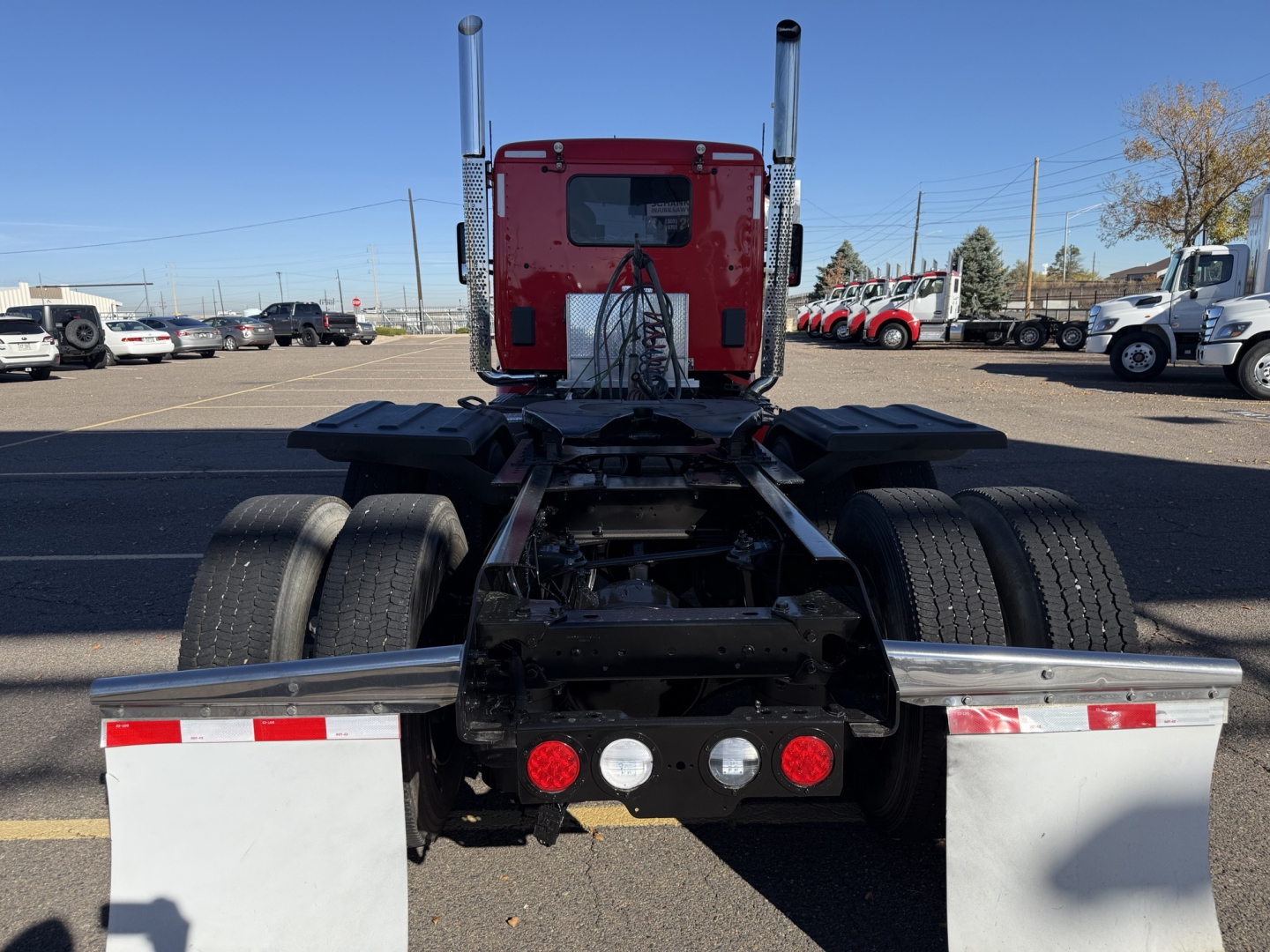 Kenworth T880 rear chassis showing dual rear axles and exhaust stacks in red cab, with a symmetric rear bumper and lights.