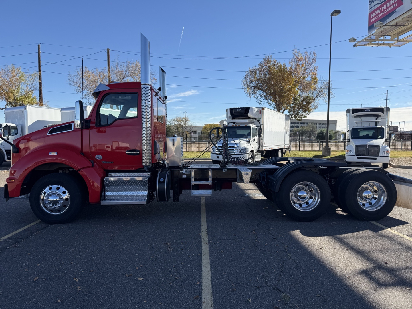 Kenworth T880 tractor unit side view showing red cab, chrome fuel tanks, and dual rear axles with silver rims.