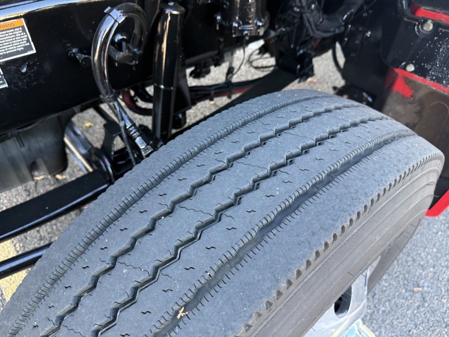 Truck wheel well with tire tread close-up under Kenworth T880 chassis showing air lines and frame components.