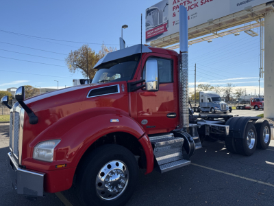 Kenworth T880 daycab tractor in red, side view showing front grille, chrome mirrors, dual rear axles, fueling steps, and chrome exhaust stack.
