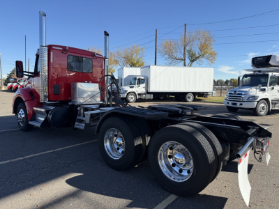 Kenworth T880 tractor cab chassis with dual rear axles, red cab, chrome exhaust stacks, metal steps, and fifth wheel mount site.