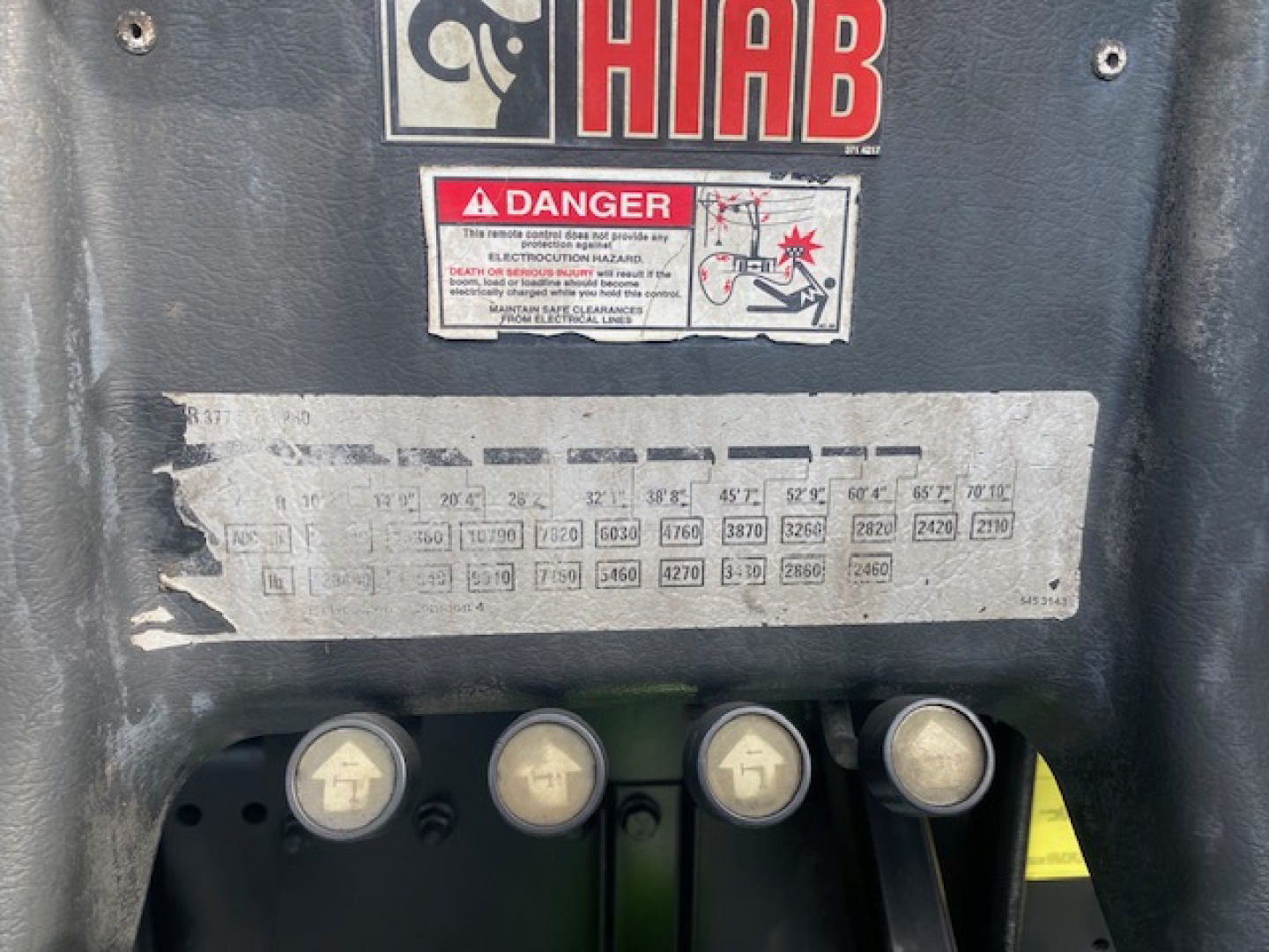 Freightliner M2-112 cab label area showing HIBAD danger sticker and a faded capacity/spec chart with four round control knobs beneath.
