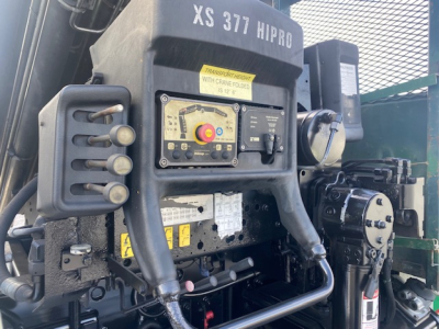 Crane truck cabin area showing controls with yellow safety button and control panel, compact hydraulic lines, and label XS 377 HI PRO.