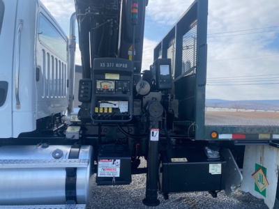Crane-equipped Freightliner M2-112 truck side view showing crane controls and operator platform with labels and warning decals.