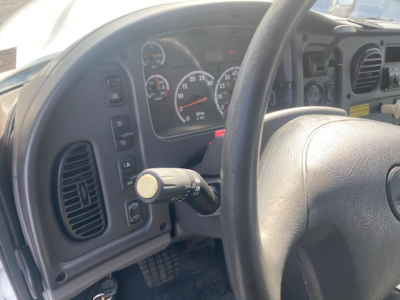 Dashboard and steering wheel of a Freightliner M2-112 crane truck showing gauge cluster and control stalks.