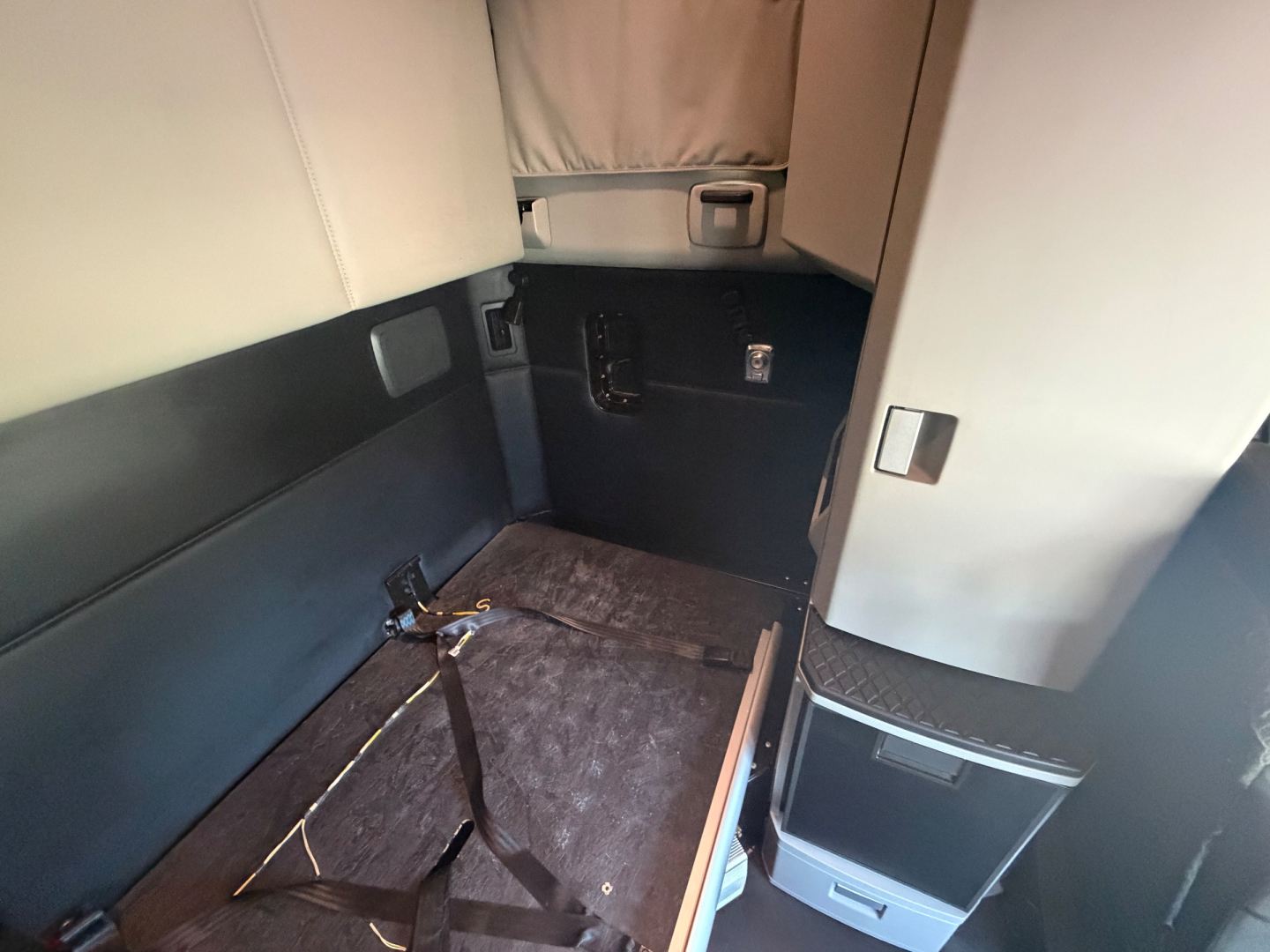 Kenworth T680 cab interior showing sleeper area with seat belt and storage compartments.