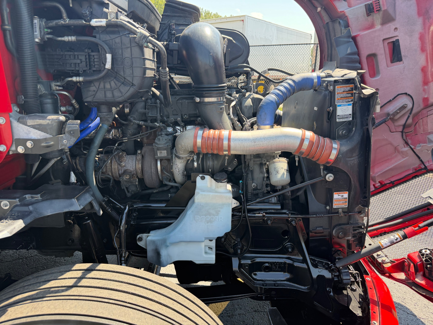 Kenworth T680 engine bay showing turbocharger and hoses, with visible engine components and radiator area.