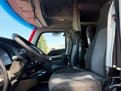 Kenworth T680 truck interior cabin view showing steering wheel and driver seat with overhead storage and sun visor