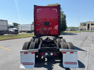 Kenworth T680 rear view showing fifth wheel, dual rear axles, mud flaps with Kenworth logos, and red sleeper cab. VIN and stock not visible.