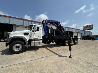 Truck-mounted crane: white Mack GR64F cab with blue hydraulic crane arms, support outriggers deployed, crane stabilizer legs visible, stock number 73752, VIN 1M2GR4GC9VM060513