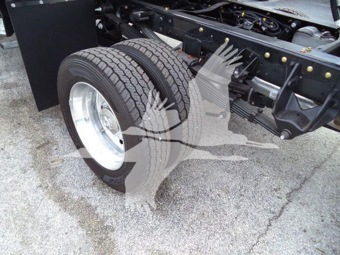 Truck rear dual tires and chassis with suspension components visible; no legible labels or text readable on components.