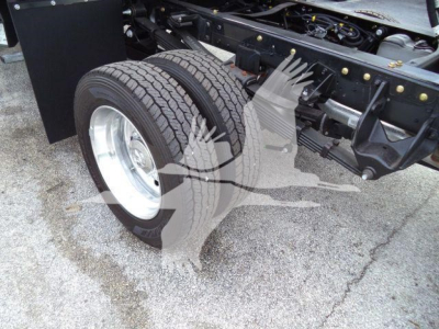 Truck rear dual tires and chassis with suspension components visible; no legible labels or text readable on components.