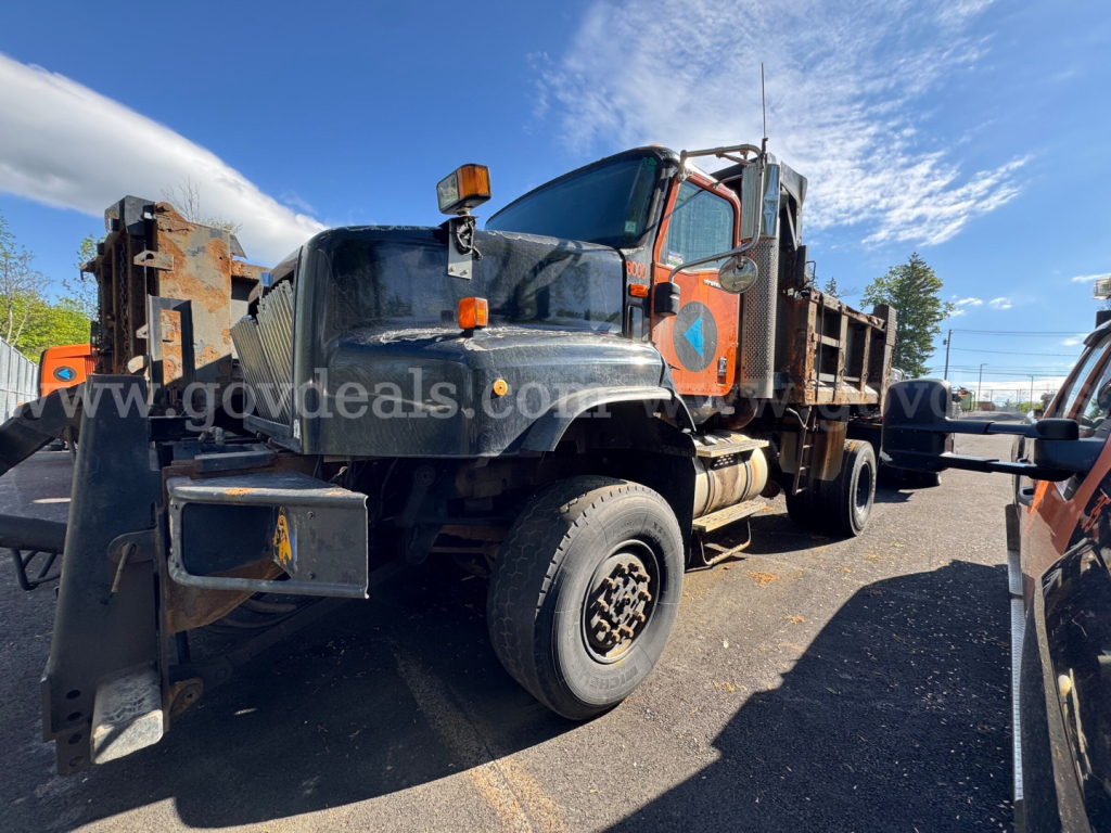 International 5600i dump truck in-service view showing front-left and side with mounted dump bed and orange cab accents.