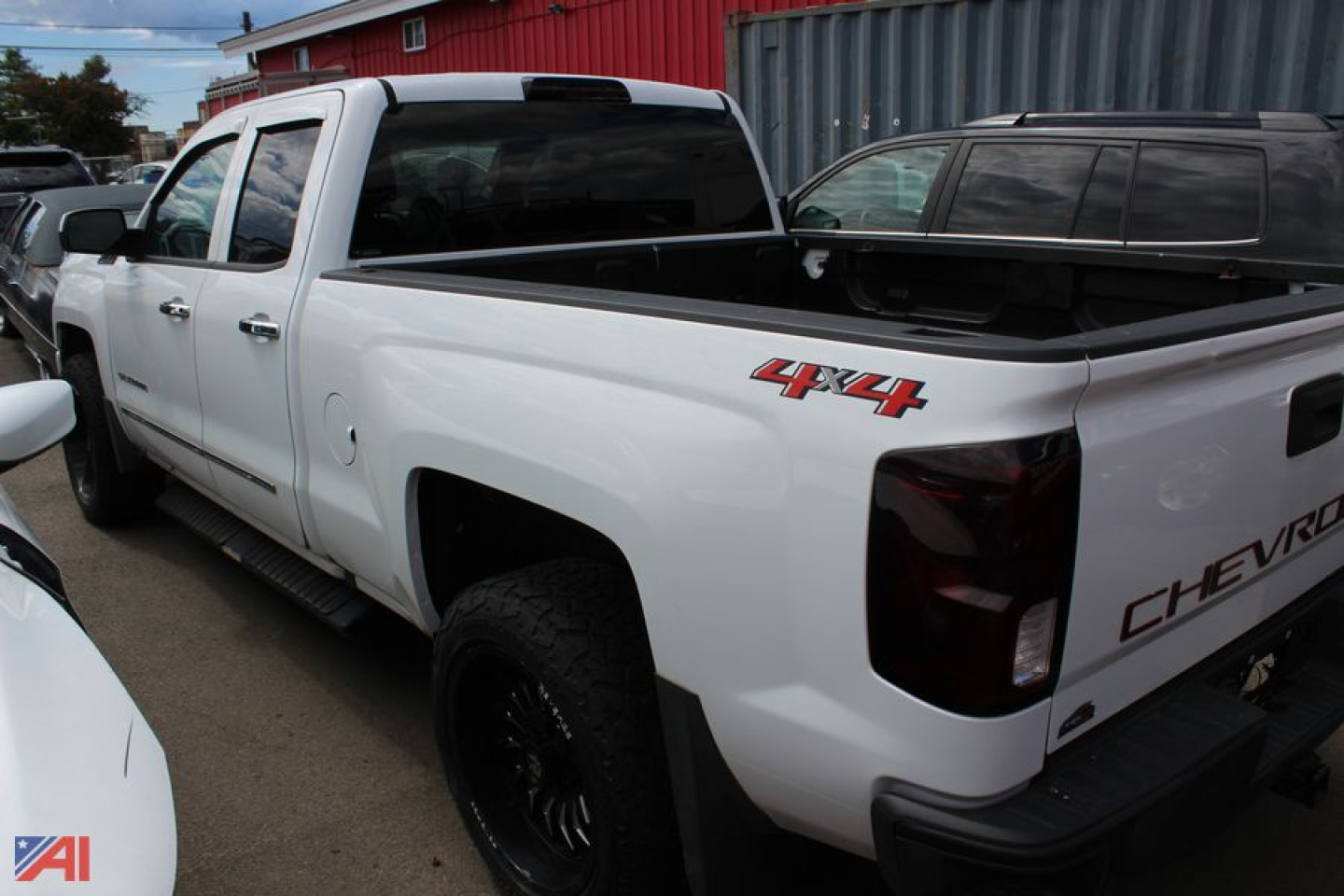 Chevrolet Silverado 1500 pickup 4x4 in white, crew cab with bed cap and tonneau; side view showing 4x4 badge on rear quarter panel.