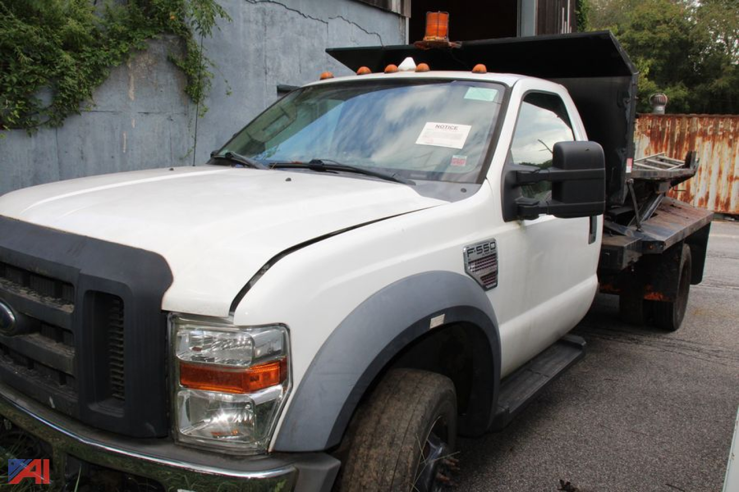 Ford F-550 Super Duty with flatbed showing chipped white cab and black front grille, orange light bar on roof, dually rear wheel area, utility work truck.