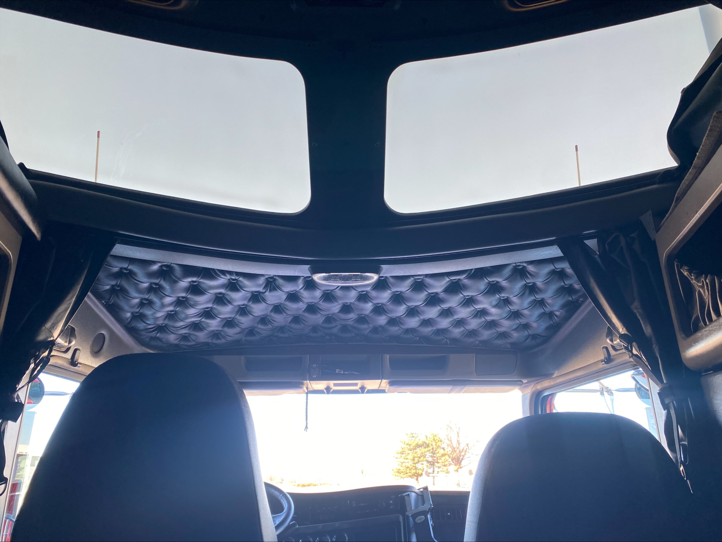 Kenworth W900L cab interior roof view with quilted headliner and front seats, from rear cabin perspective.