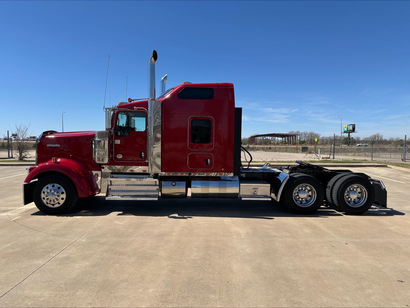 Kenworth W900L truck in side profile view showing red cab and chrome exhaust stacks.