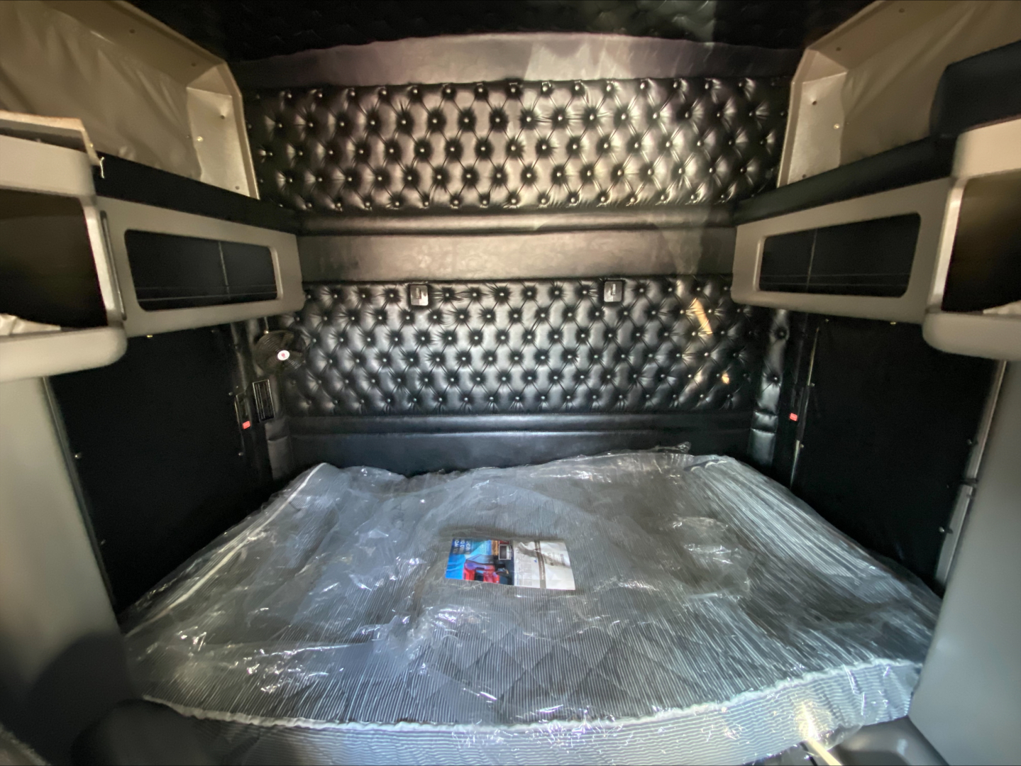 Kenworth W900L sleeper cab interior cargo area with padded quilted walls and upper storage compartments.