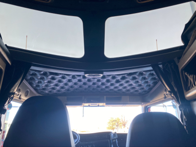 Kenworth W900L cab interior roof view with quilted headliner and front seats, from rear cabin perspective.