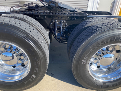 Kenworth W900L tandem axle truck chassis view with dual rear tires and chrome wheels showing Bridgestone tires and drivetrain components.