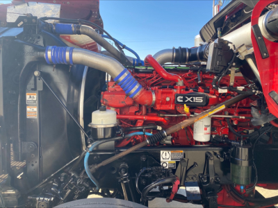 Kenworth W900L engine bay showing CX15 diesel engine, red engine block, blue silicone hoses, air intake, coolant reservoir, and various components.