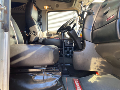 Kenworth W900L truck interior driver seat view showing steering wheel and dashboard, black leather seats, and right-hand drive controls.