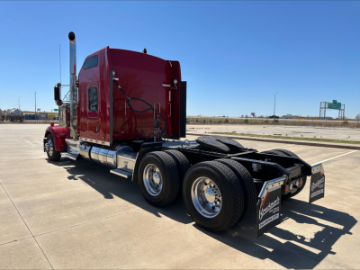 Kenworth W900L tractor from the rear quarter showing dual rear axles and fifth wheel with metal fenders and chrome fuel tanks.
