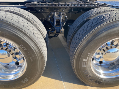 Kenworth W900L rear/central chassis showing dual rear axles and suspension with chrome wheels and tires; no readable text visible on components.