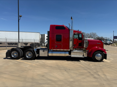 Kenworth W900L semi truck side profile showing red cab and chrome fuel tanks. Side steps, rear dual axles, and exhaust stacks visible.