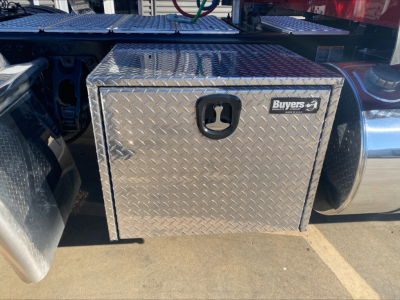 Kenworth W900L fuel/aluminum diamond-plate toolbox mounted behind cab with Buyer's logo on toolbox door.