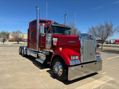 Kenworth W900L truck in red with chrome grille, dual tall exhaust stacks, and polished bumper. Visible text includes KENWORTH on grille, and truck features.