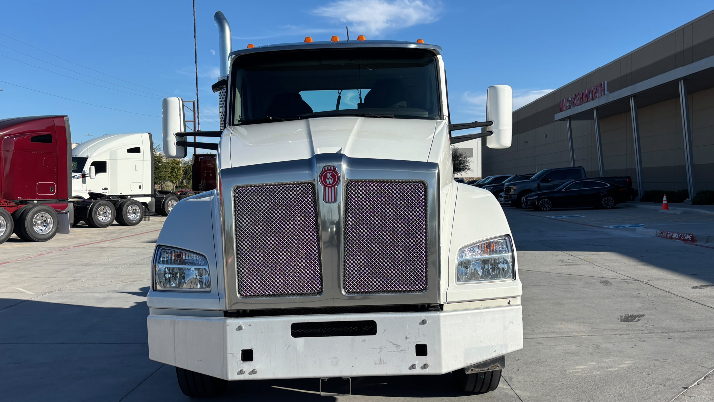 Kenworth T880 straight-on front view showing large grille, rectangular headlights, and white cab with side mirrors.