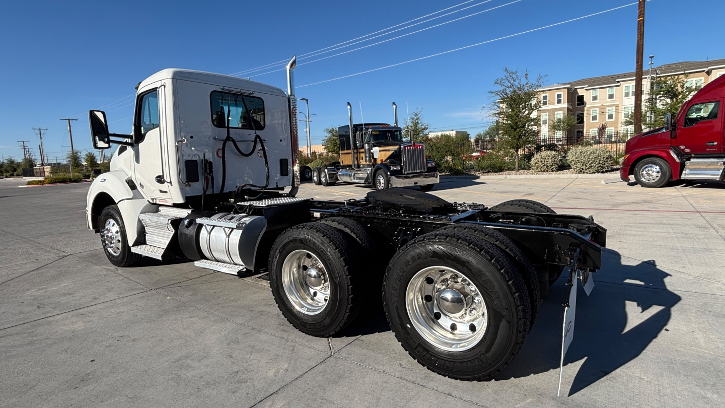 Kenworth T880 tractor chassis with front cab in view showing dual rear axles and fuel tanks; VIN tag not visible; daytime outdoor lot.