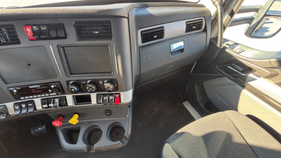 Kenworth T880 dash area showing steering wheel, instrument panel, climate controls, and cup holders in cab interior.