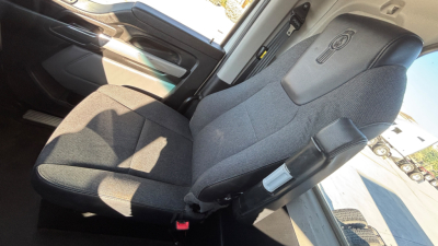 Kenworth T880 cab interior showing driver seat and door panel with light gray upholstery and seat belt buckle.
