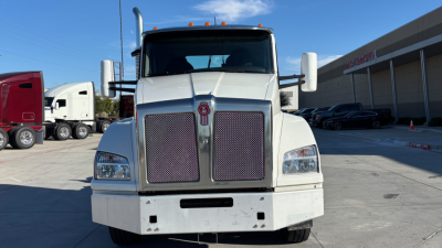 Kenworth T880 straight-on front view showing large grille, rectangular headlights, and white cab with side mirrors.