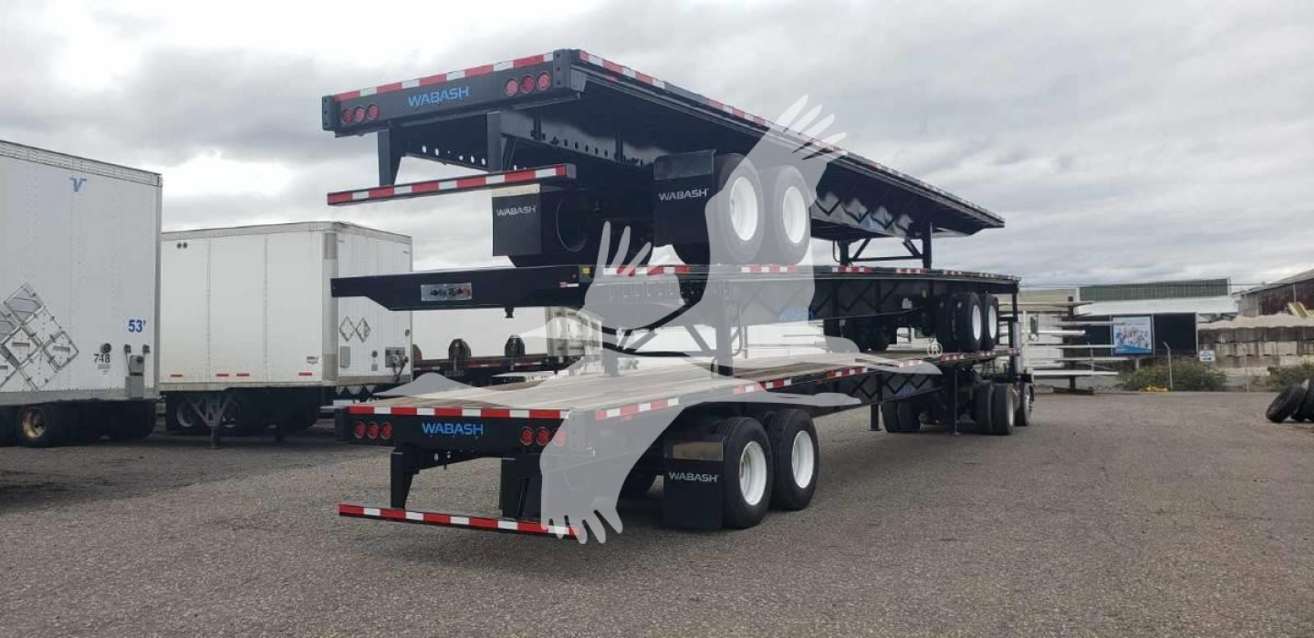 Wabash steel air slider trailer on a lot, dual-axle with extended flatbed and rear ramps visible.