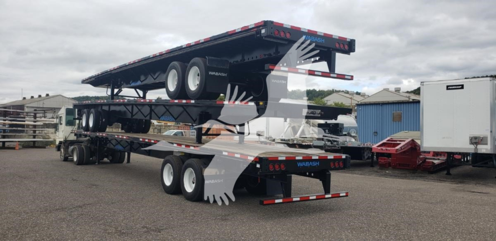 Trailer flatbed with steel air slider in stacked position on a multi-axle trailer showing Wabash branding and platform steps.