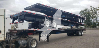 Flatbed trailer with multiple steel air slider deck sections, Wabash branding, black and silver color, dual tandem axles, rear ramps visible.
