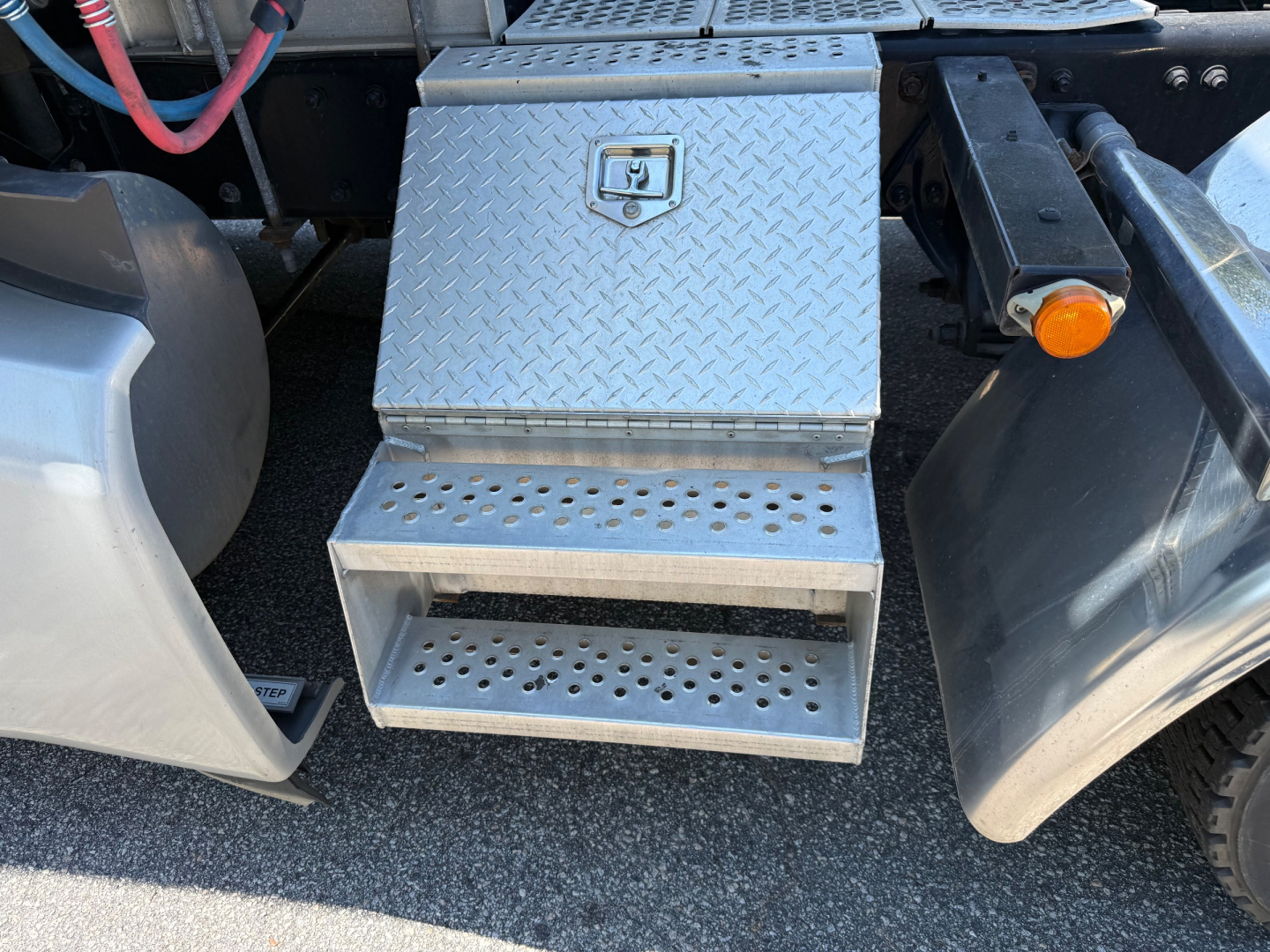 Kenworth T680 step box and underside view showing diamond plate steel toolbox and steps under sleeper cab area.