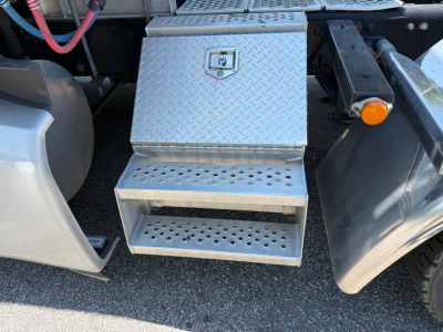 Kenworth T680 step box and underside view showing diamond plate steel toolbox and steps under sleeper cab area.