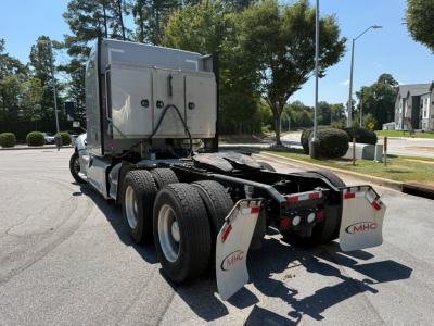 Kenworth T680 tractor rear view showing dual rear axles and mud flaps with MHC logo.