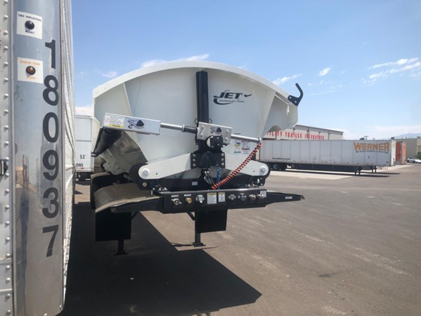 Jet Jet 40' air ride side dump trailer showing front hopper, lifting mechanism, and hydraulic components with a ladder and mounting frame.