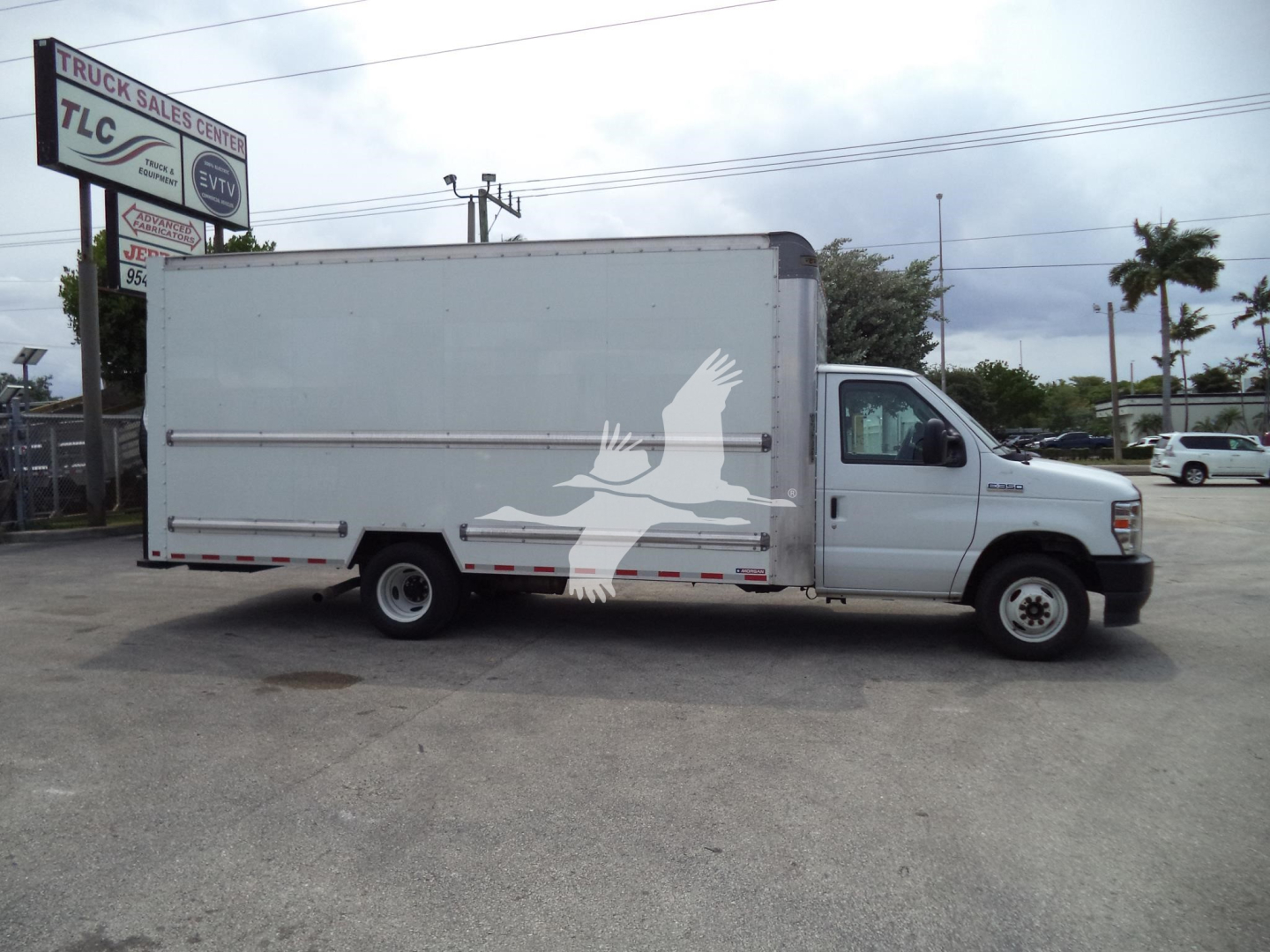 Ford E350 box truck side view with a white Freightliner-like cargo box featuring a large bird logo on the side.