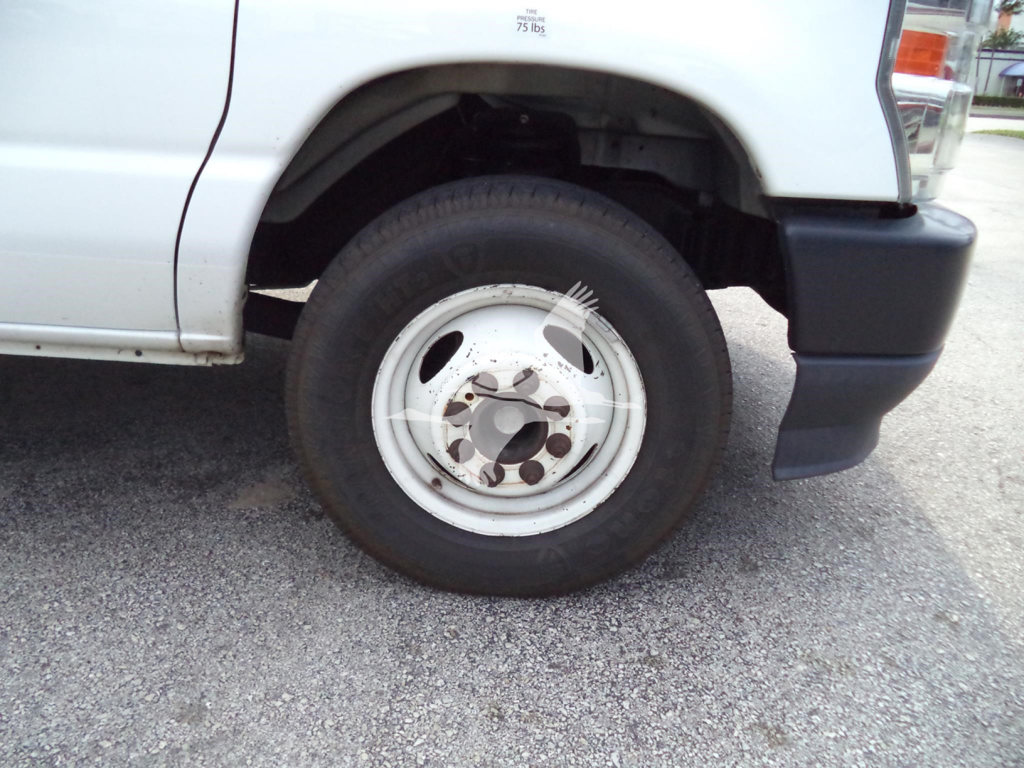 Ford E-Series van front wheel and fender showing wheel and tire details.