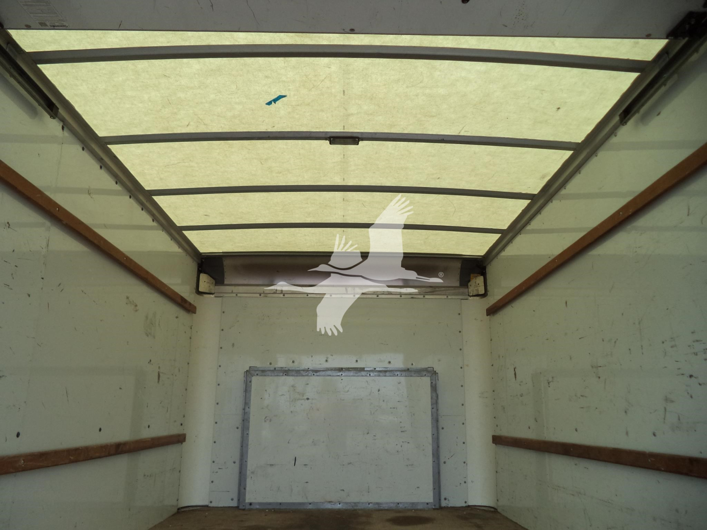 Truck cargo area interior showing empty box with metal walls and rear doors in a Ford E350 high cube cargo van.