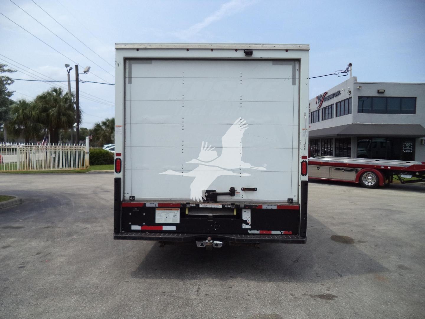 Rear view of a 2022 Ford E350 box truck with a white cargo door featuring a white bird graphic; taillights, bumper, and hitch visible.